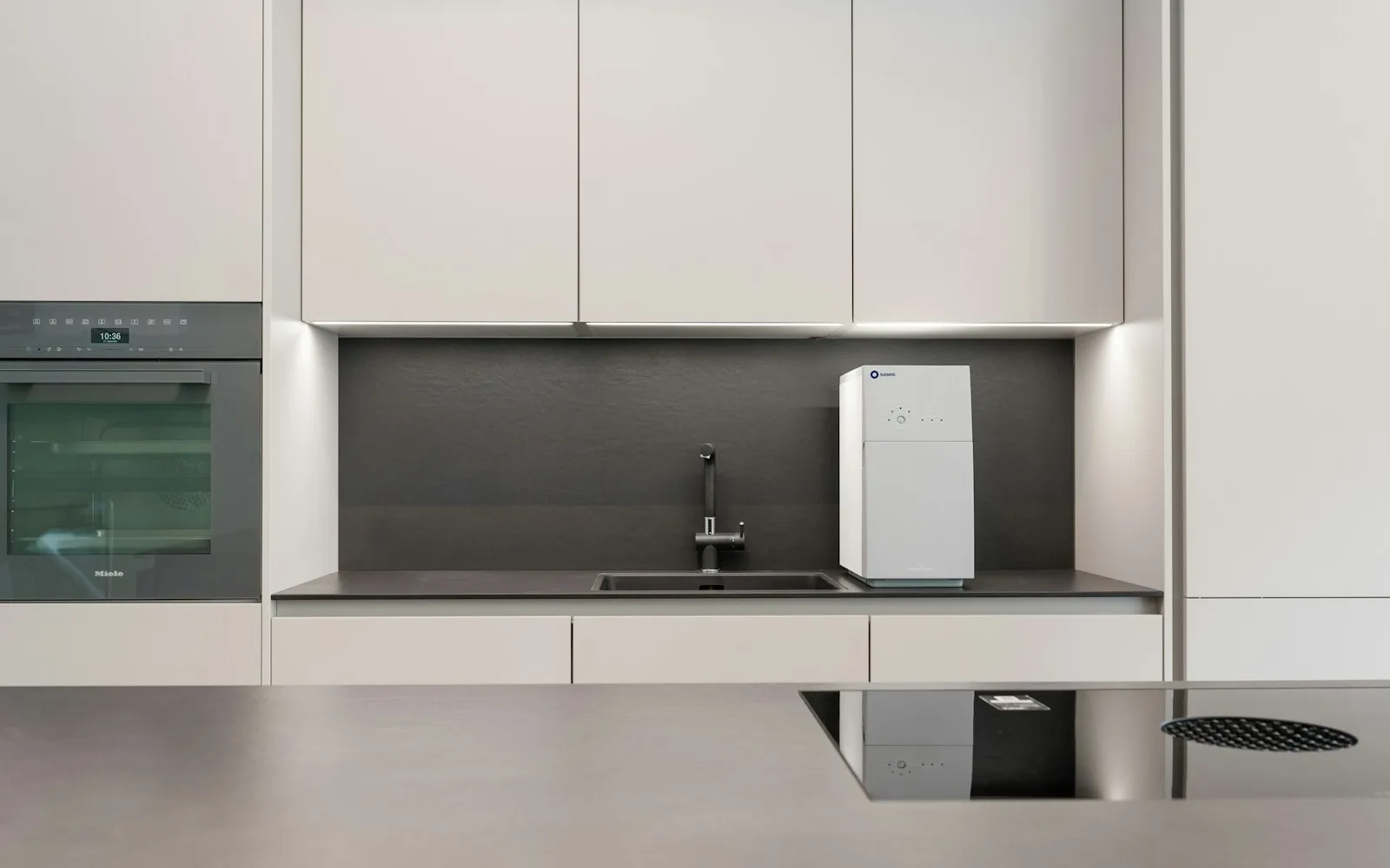 Aparelho de água branco sobre bancada de cozinha moderna minimalista com armários brancos